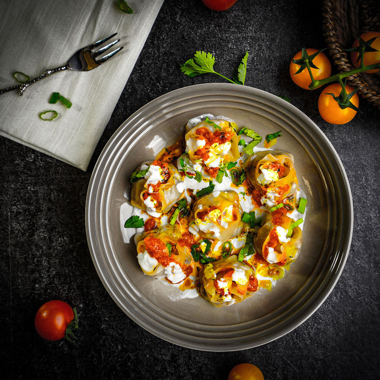 Dumplings topped with yogurt and tomato sauce
